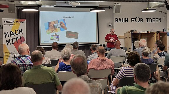 Publikum, davor Referent Uwe Renners, der etwas erklärt.